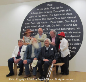 Zero artists (or spouses) with the Zero Manifesto on wall behind them at the Amsterdam Stedelijk Museum, (4 July 2015). Back row l. to r.: Elizabeth Goldring Piene, Christian Megert, Jan Henderikse and unidentified woman. Front row l. to r.: unidentified man, herman de vries and Uli Pohl.